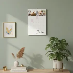 Geburtstagskalender hängend an einer grünen Wand über einem modernen Sideboard in einer hellen Wohnung.